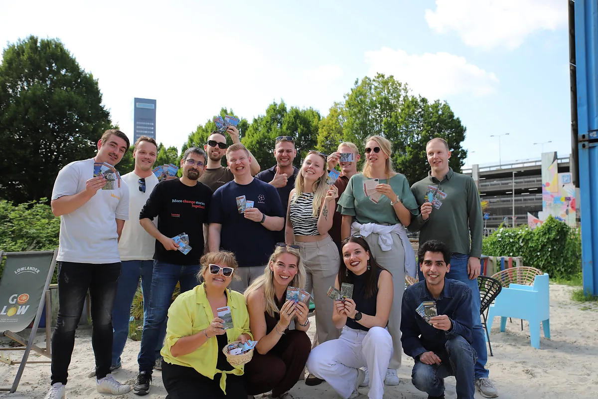 Een groep leden met kaartjes van Paper Trails in de hand op het stadsstrand